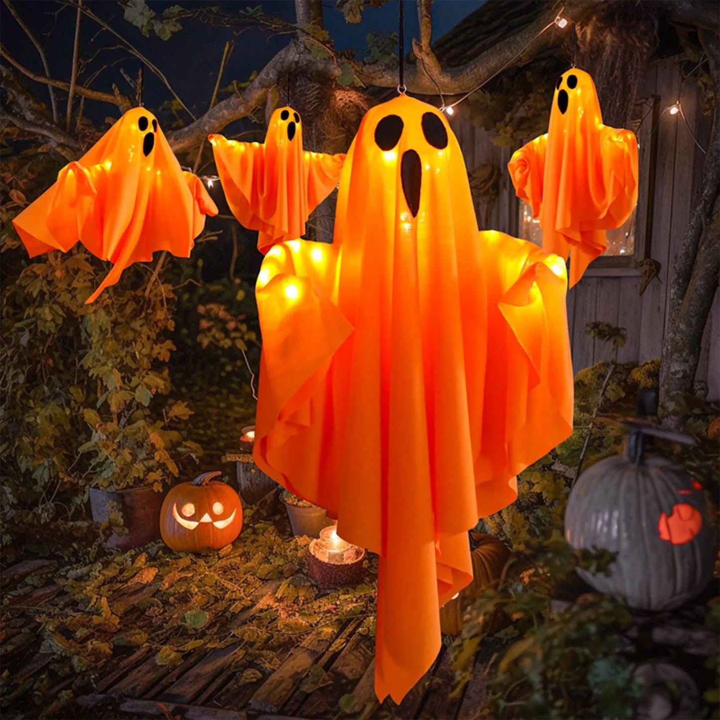 Multiple light-up ghosts near a porch with pumpkins.