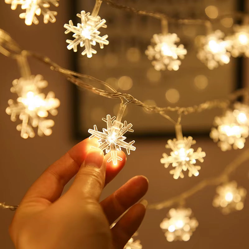 Hand holding a snowflake LED cover on the warm white Christmas string lights