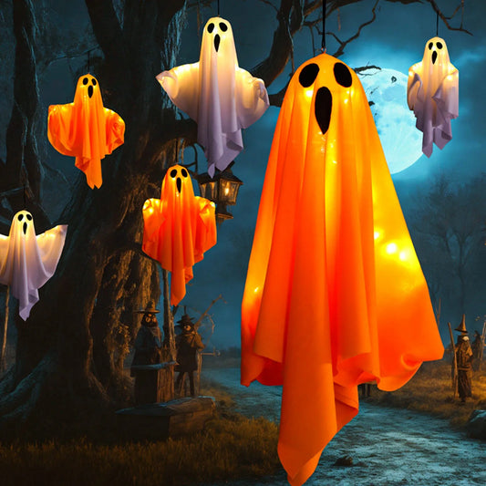 Group of white and orange light-up hanging ghosts floating in a forest at night.