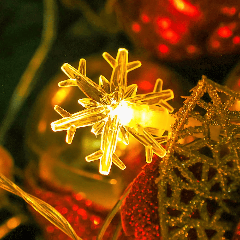 Close-up of glowing snowflake LED ornament resting on a Christmas branch