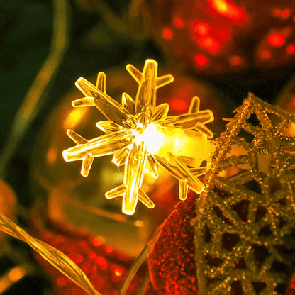 Close-up of glowing snowflake LED ornament resting on a Christmas branch
